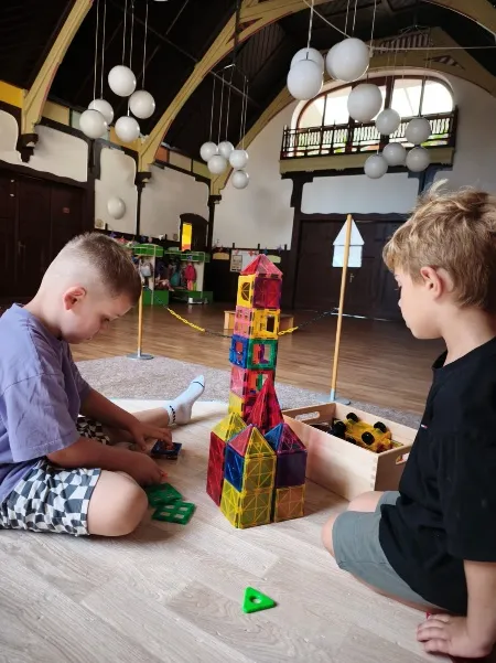 Zwei Jungen bauen im Jugendstilsaal einen hohen Turm aus bunten Magnetbausteinen.